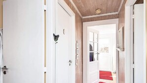 Um corredor com portas brancas, uma decoração de borboleta e um tapete vermelho que leva a um quarto com janela.