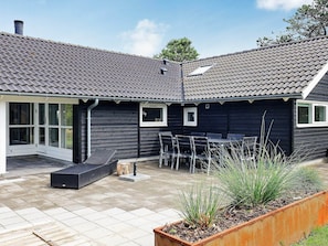 A modern house with a dark exterior, a tiled roof, and a patio area with outdoor furniture. - Luxury Retreat With Spa - By Traum Ferienwohnungen (Sydlangeland)