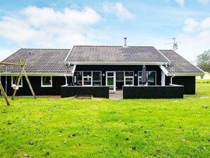 A two-story house with a tiled roof, a front porch, and a swing set.