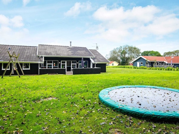 A residential area with a house, a trampoline, and a swing set.