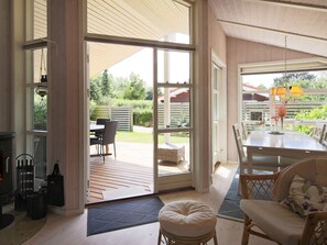 An open-plan living area with a sliding glass door leading to a patio, a dining table with chairs, and a seating area with cushions.