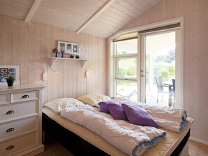 A bedroom with a bed, a dresser, a shelf with decorative items, and a window with a view of the outdoors. - 4 Person Holiday Home in Follenslev (Follenslev)