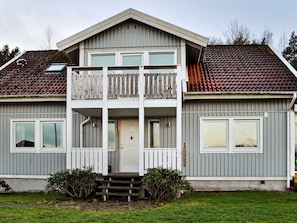 A two-story residential building with a balcony, a front door, and a small front yard. - 6 Person Holiday Home in Kode (Kode)