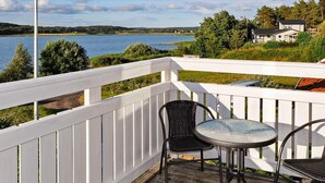 A wooden deck with a white railing, two black chairs, and a small round table. - 6 Person Holiday Home in Kode (Kode)