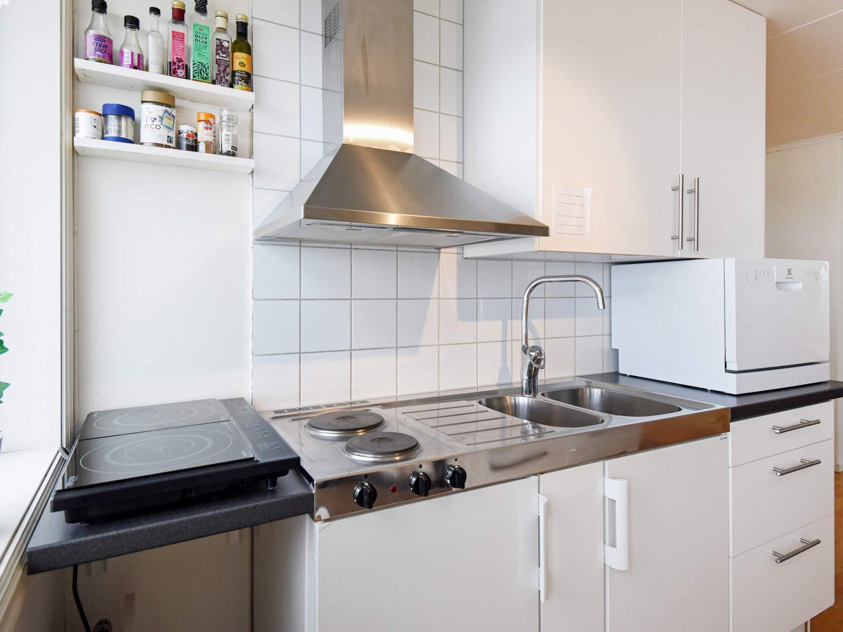 A modern kitchen with a gas stove, stainless steel sink, and white cabinets.