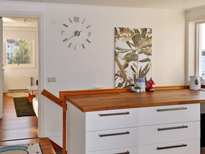 A modern kitchen with a wooden countertop, white cabinets, a wall clock, and a decorative plant. - 6 Person Holiday Home in Kode (Kode)