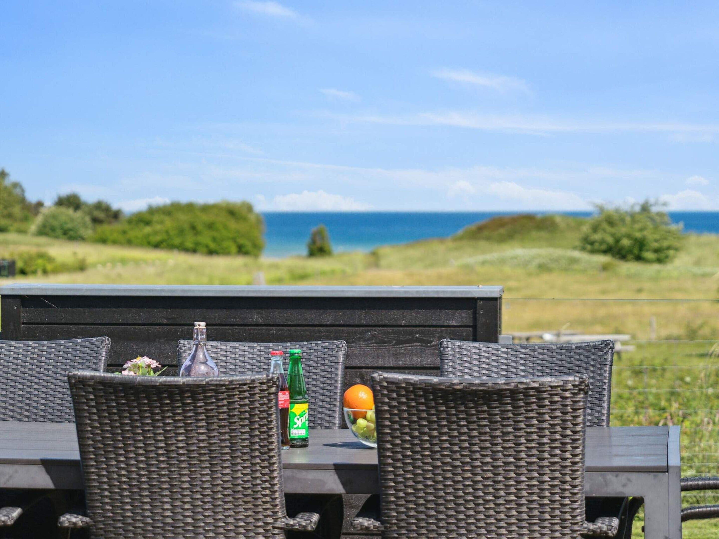 An outdoor dining area with wicker furniture, a bottle of Sprite, and a bowl of fruit.