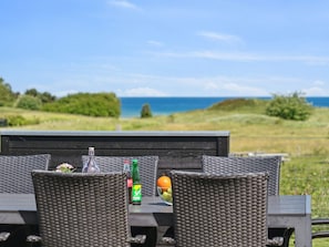 An outdoor dining area with wicker furniture, a bottle of Sprite, and a bowl of fruit. - 5 Star Holiday Home in Glesborg (Glesborg)