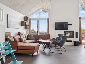 A modern living room with a sectional sofa, a coffee table, and a fireplace. - 5 Star Holiday Home in Glesborg (Glesborg)