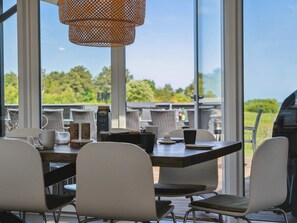 An outdoor dining area with a table set for two, chairs, and a hanging light fixture. - 5 Star Holiday Home in Glesborg (Glesborg)