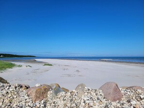 A beach with white sand, pebbles, and large rocks. - 5 Star Holiday Home in Glesborg (Glesborg)