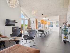 Et moderne interiør med spiseplads, køkken og et stort vindue.
