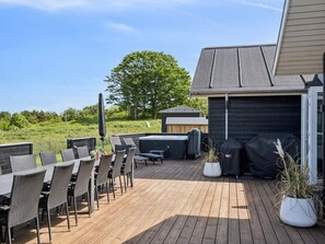 Eine Holzterrasse mit Gartenmöbeln, einem Grill und einem Whirlpool.