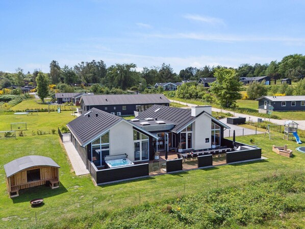 Ein modernes Haus mit einer großen Terrasse, einem Whirlpool und einem eingezäunten Garten.