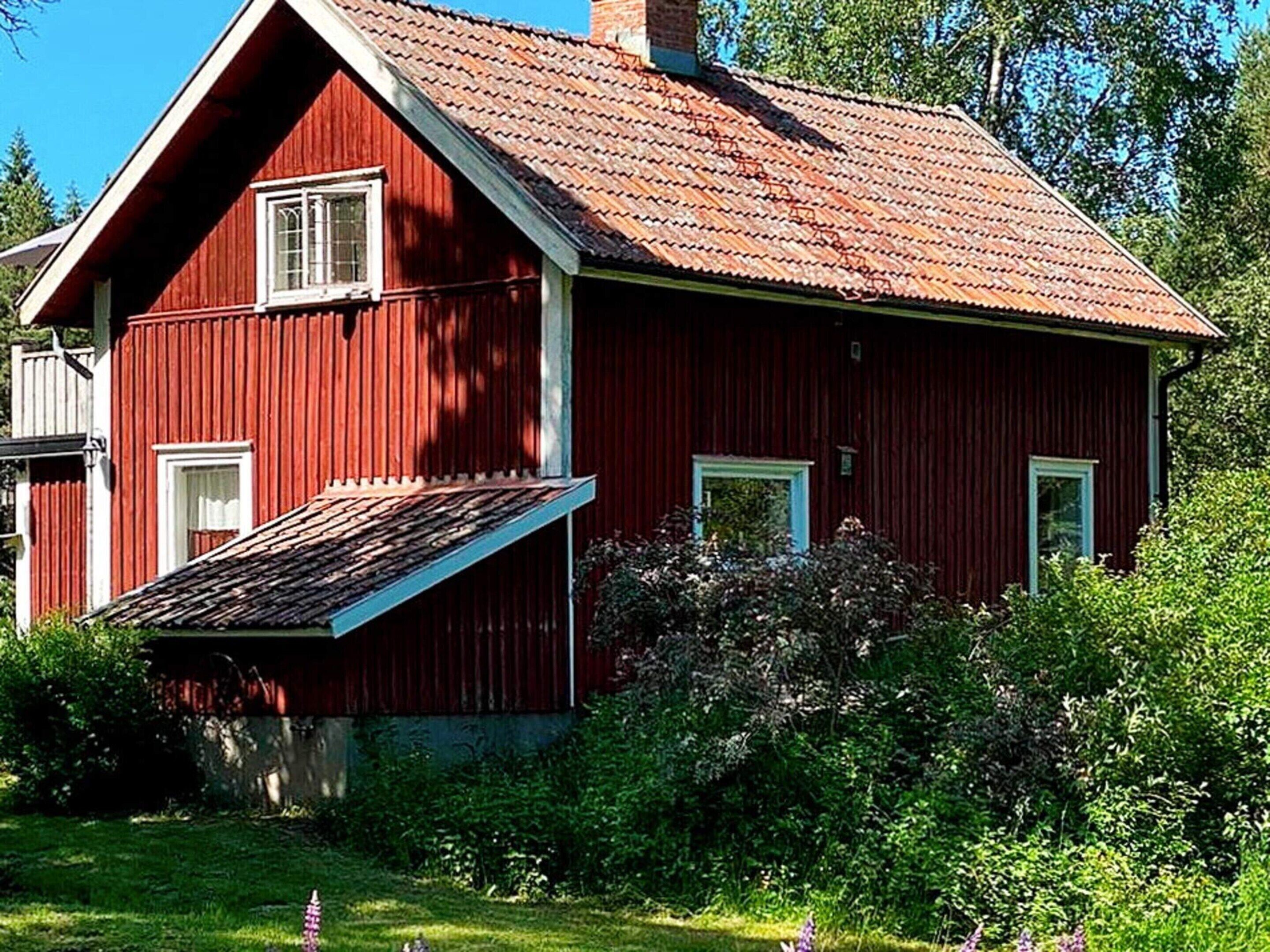 A red wooden house with a sloped roof and a small porch.