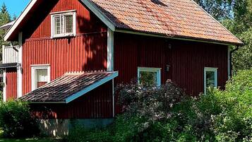 A red wooden house with a sloped roof and a small porch.