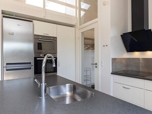 A modern kitchen with stainless steel appliances, a sink, and a walk-in closet.