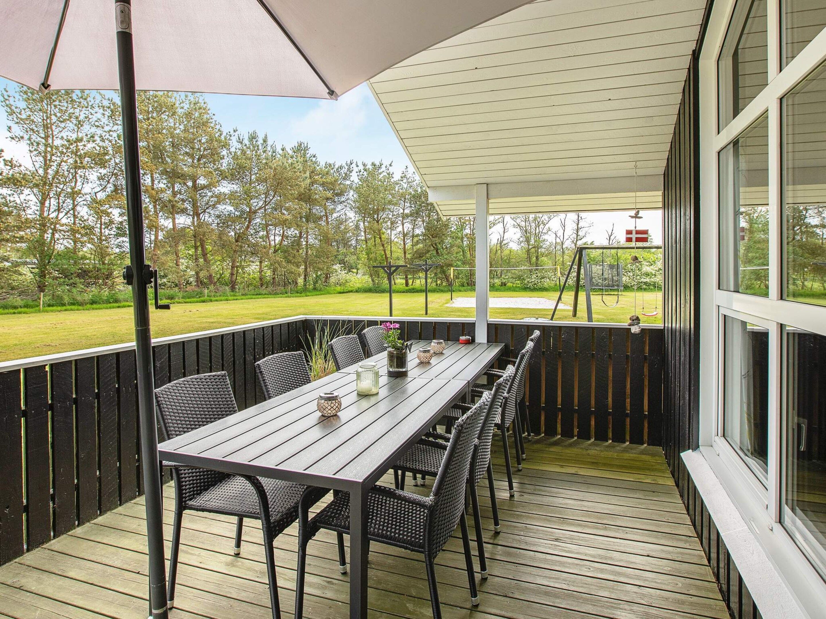 An outdoor patio with a table and chairs, a covered area, and a view of a golf course.