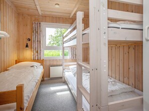 A bunk bed room with a window, a bedside lamp, and a radiator.