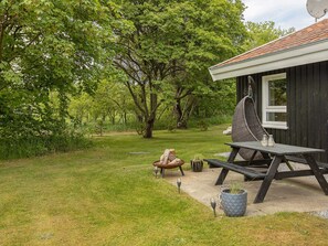 A rustic outdoor seating area with a picnic table, a hanging chair, and a small fire pit.