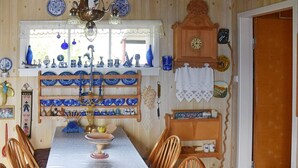 A dining area with a long table, chairs, and a variety of blue and white dishes displayed on shelves.