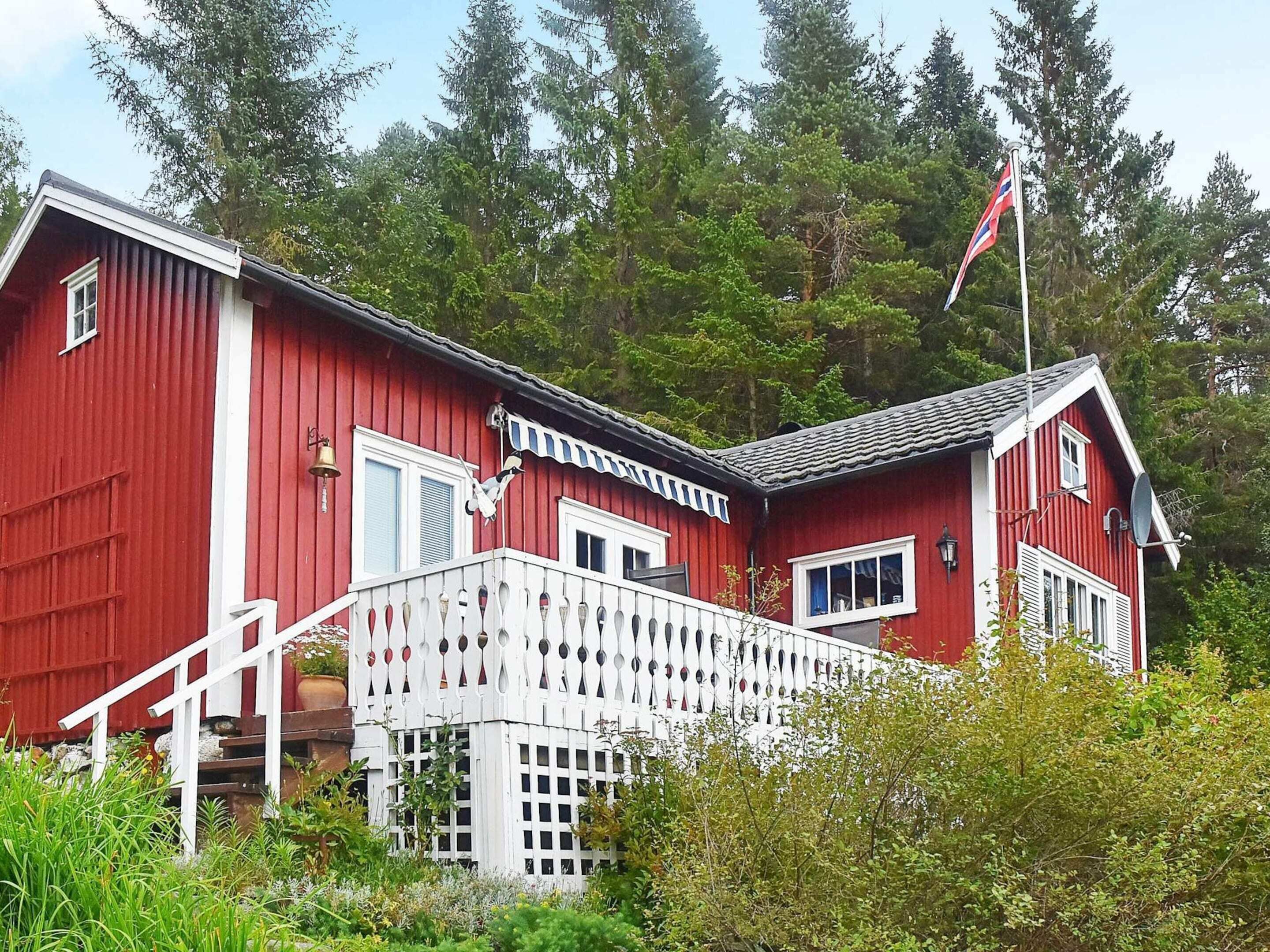 Ein rotes Holzhaus mit einem weißen Balkon, einer Flagge und einer Glocke.