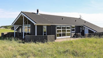 A single-story building with a sloped roof, large windows, and a wooden deck.