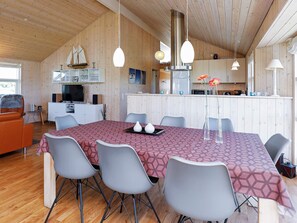 A modern kitchen with wooden cabinets, a dining area with a patterned tablecloth, and a cozy seating area with a leather sofa. - 5 Star Holiday Home in Hirtshals (Hirtshals)