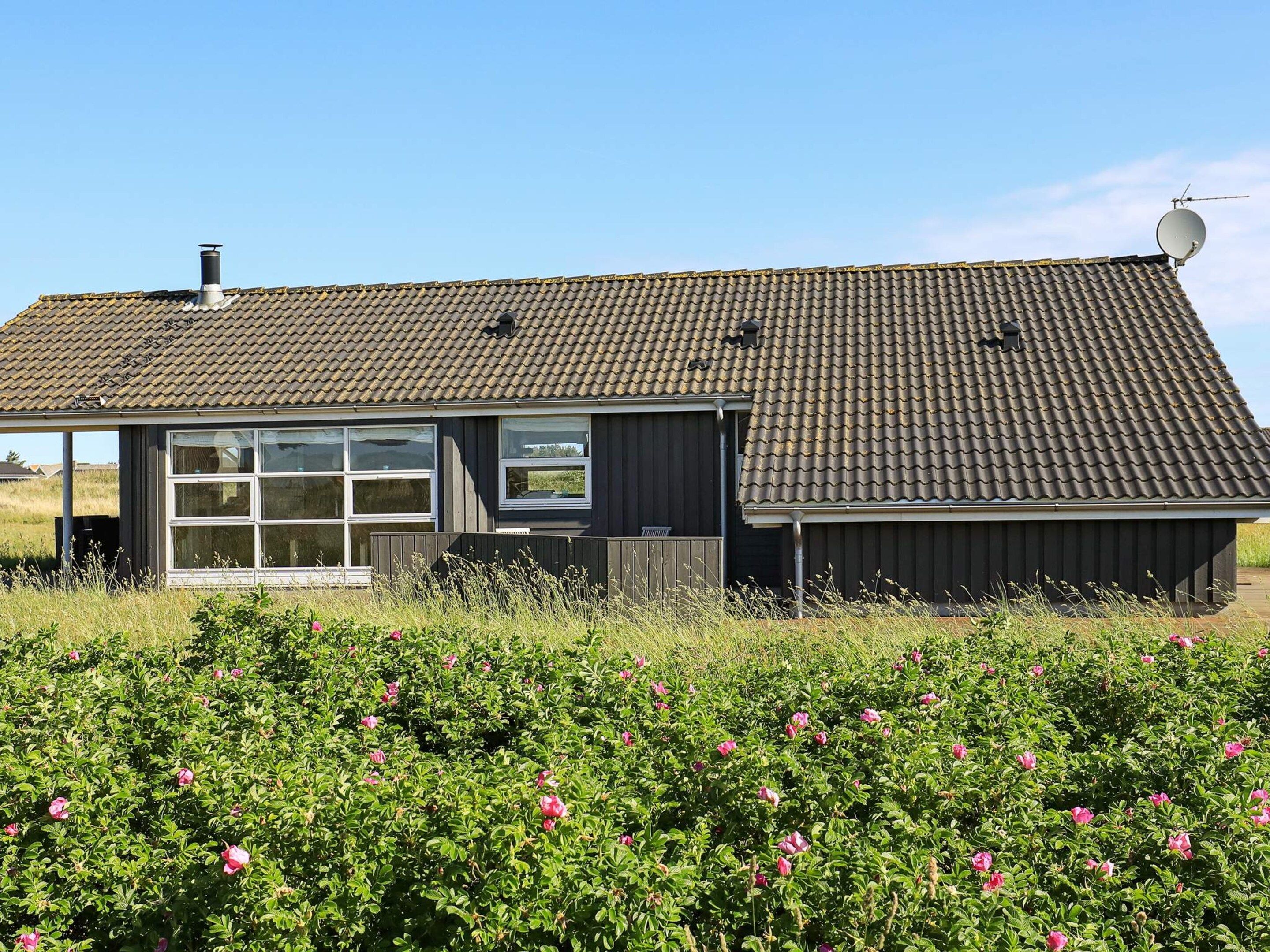 A building with a tiled roof, large windows, and a satellite dish.