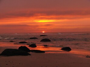 A sunset over a beach with rocks in the foreground. - 5 Star Holiday Home in Hirtshals (Hirtshals)