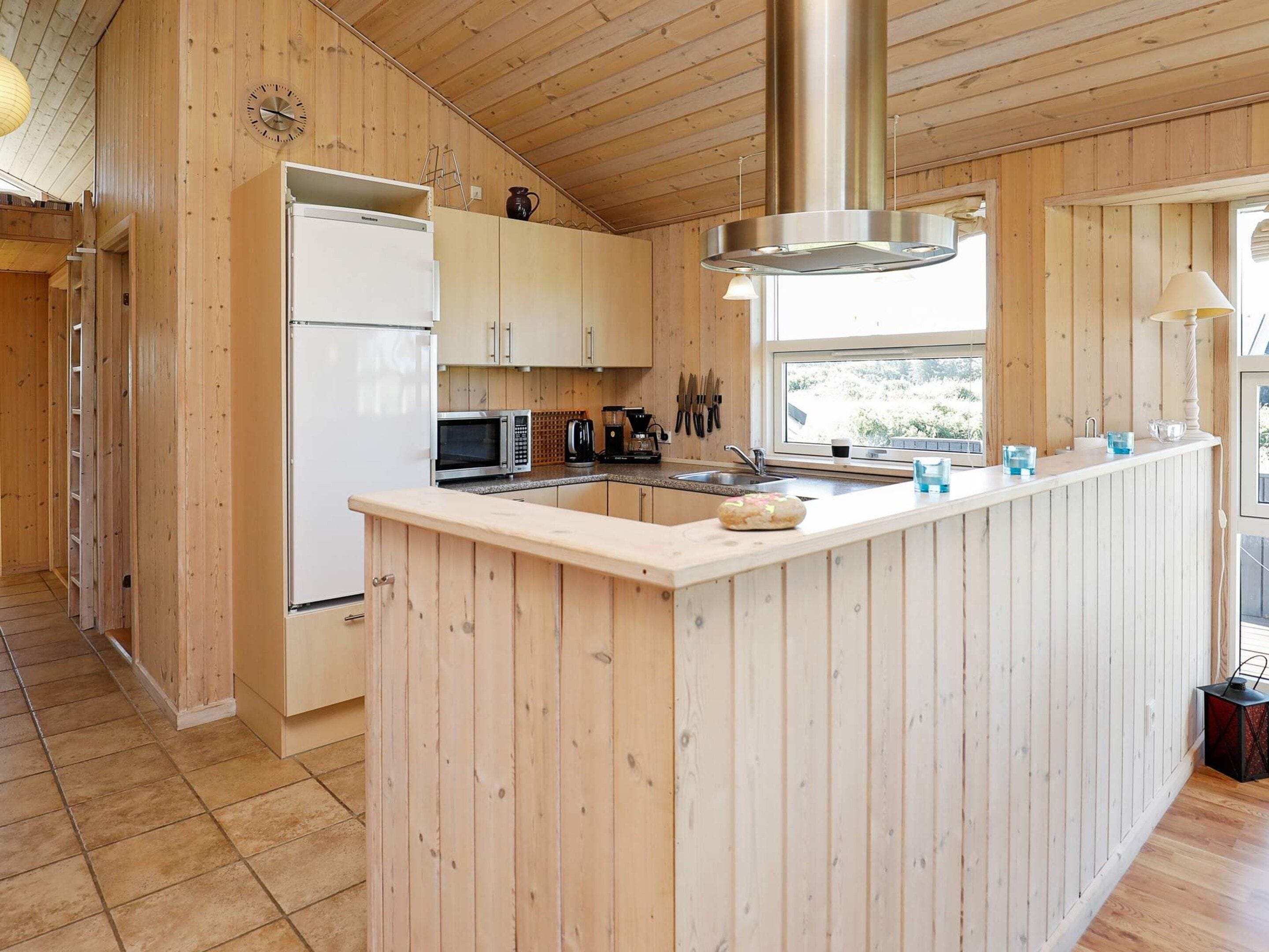 A modern kitchen with wooden cabinetry, a stainless steel range hood, and a central island.