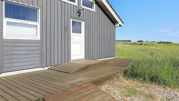 A wooden house with a porch, a door, and windows.
