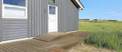 Puurakenteinen talo, jossa on kuisti, ovi ja ikkunat.