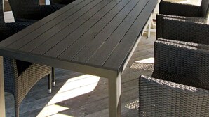 A wooden deck with a table and wicker chairs. - 5 Star Holiday Home in Rude (Bisserup)