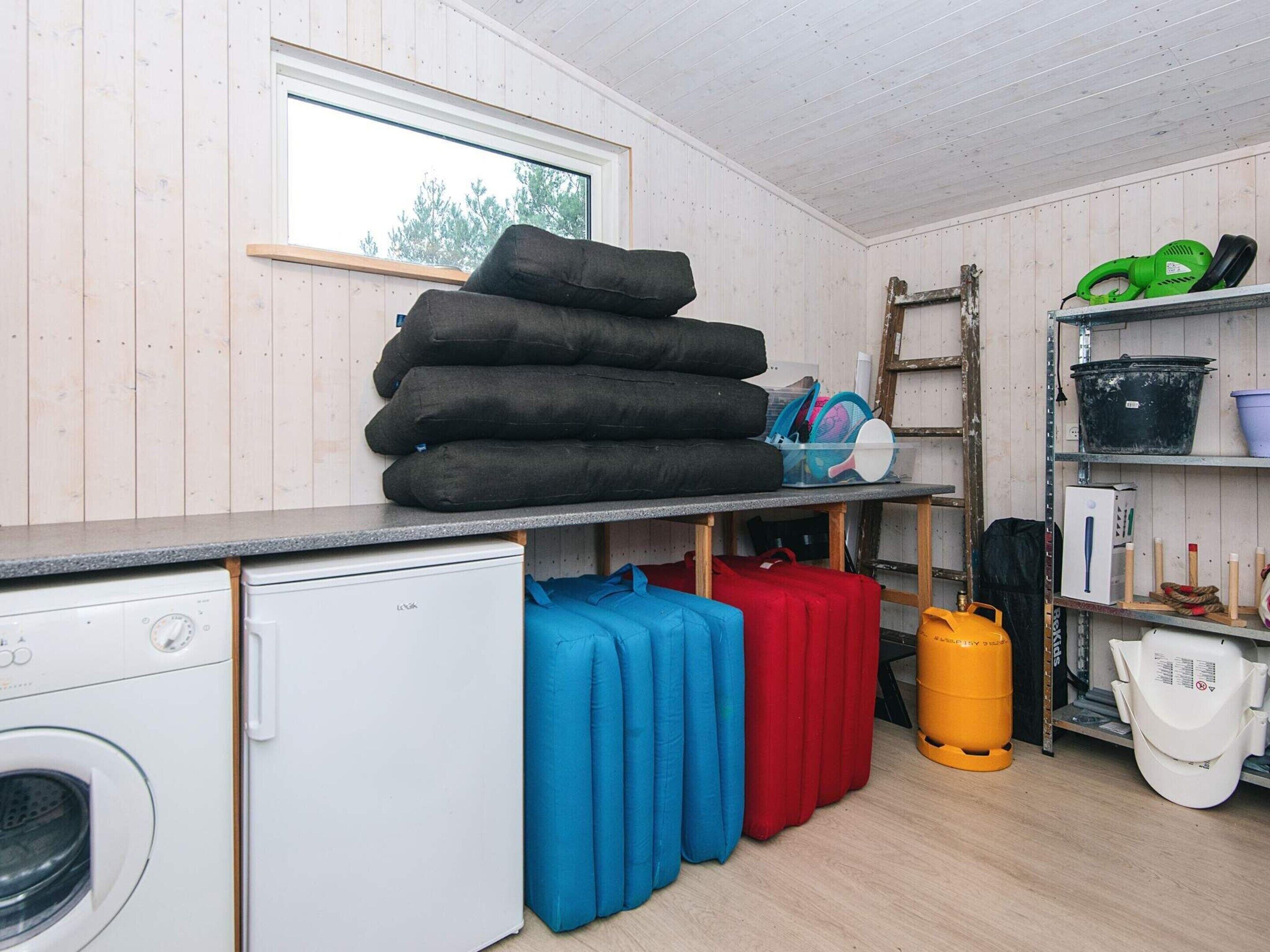 A laundry room with a washing machine, stacked towels, and various cleaning supplies.