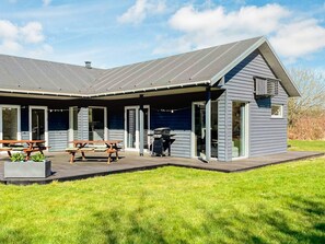 A two-story building with a covered patio area, a barbecue grill, and a picnic table. - 4 Star Holiday Home in Glesborg (Glesborg)