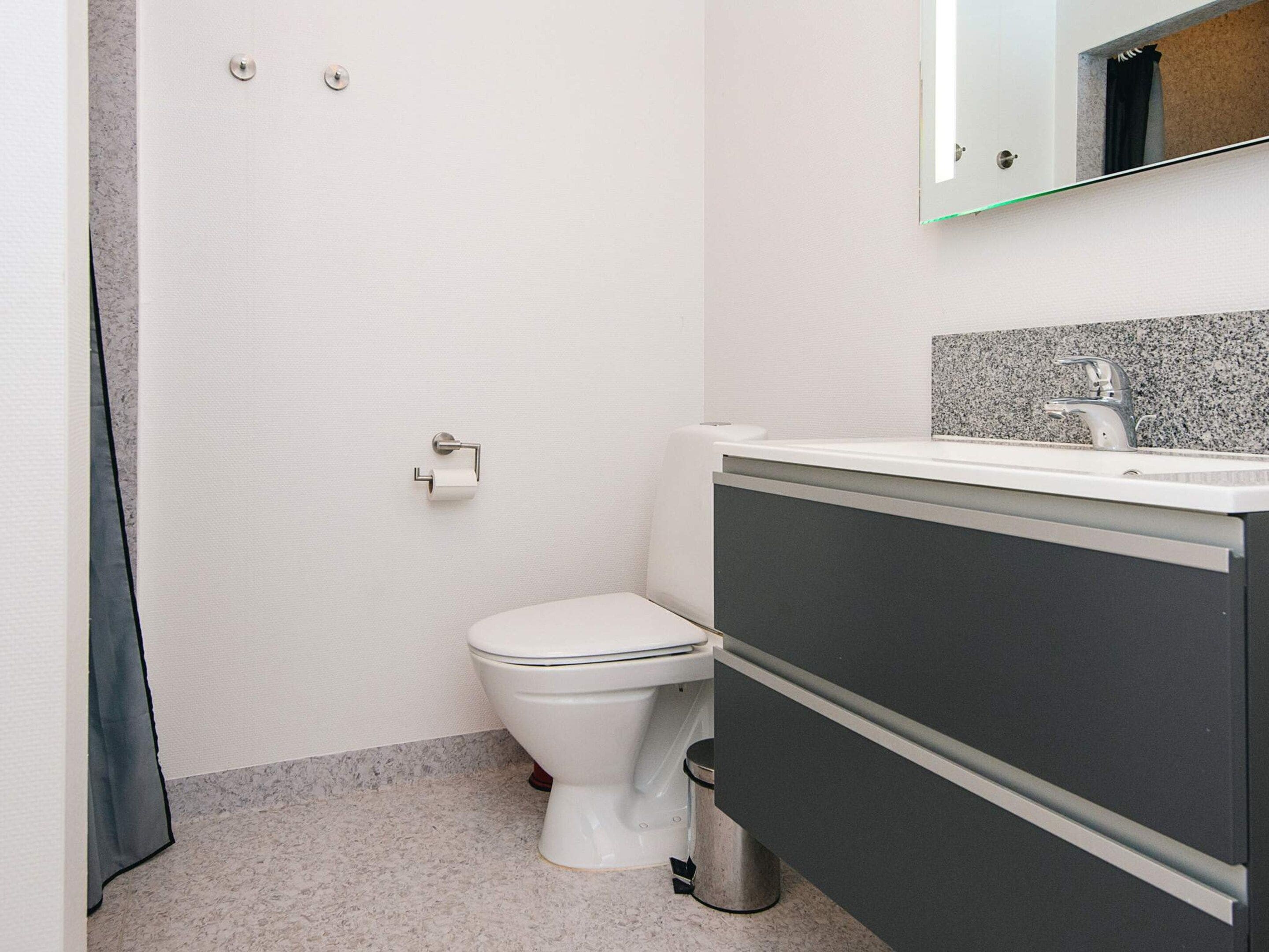A bathroom with a toilet, a sink, and a trash can.