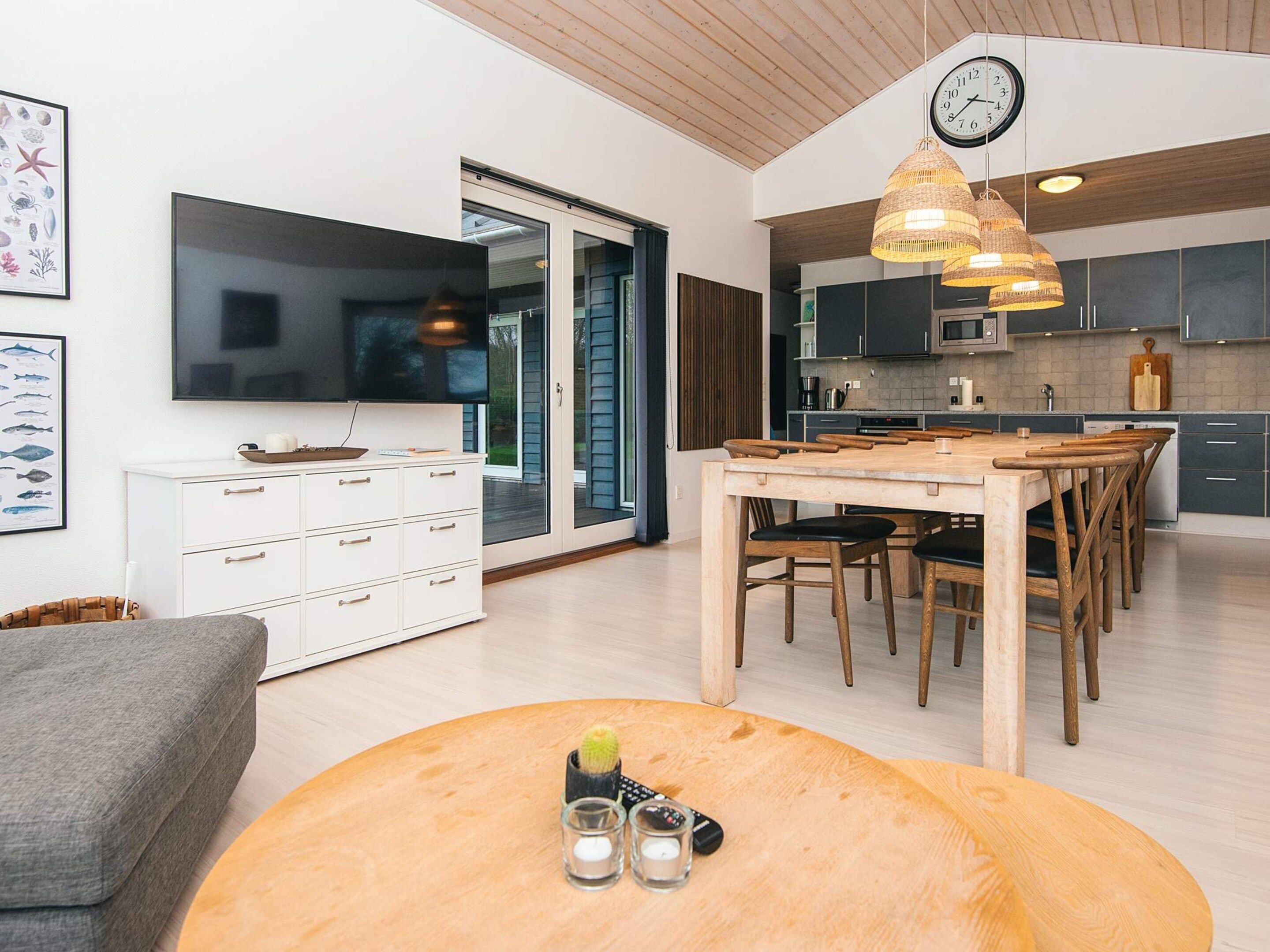 Una cocina moderna con comedor, muebles de madera y un televisor de pantalla plana grande.