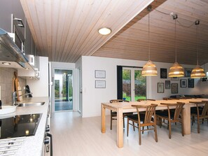 A modern kitchen with a dining area, wooden ceiling, and pendant lighting. - 4 Star Holiday Home in Glesborg (Glesborg)
