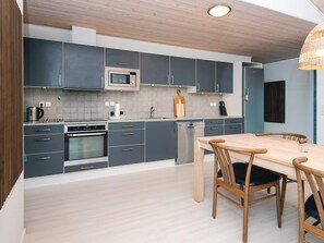 A modern kitchen with grey cabinets, stainless steel appliances, and a wooden dining table with chairs.