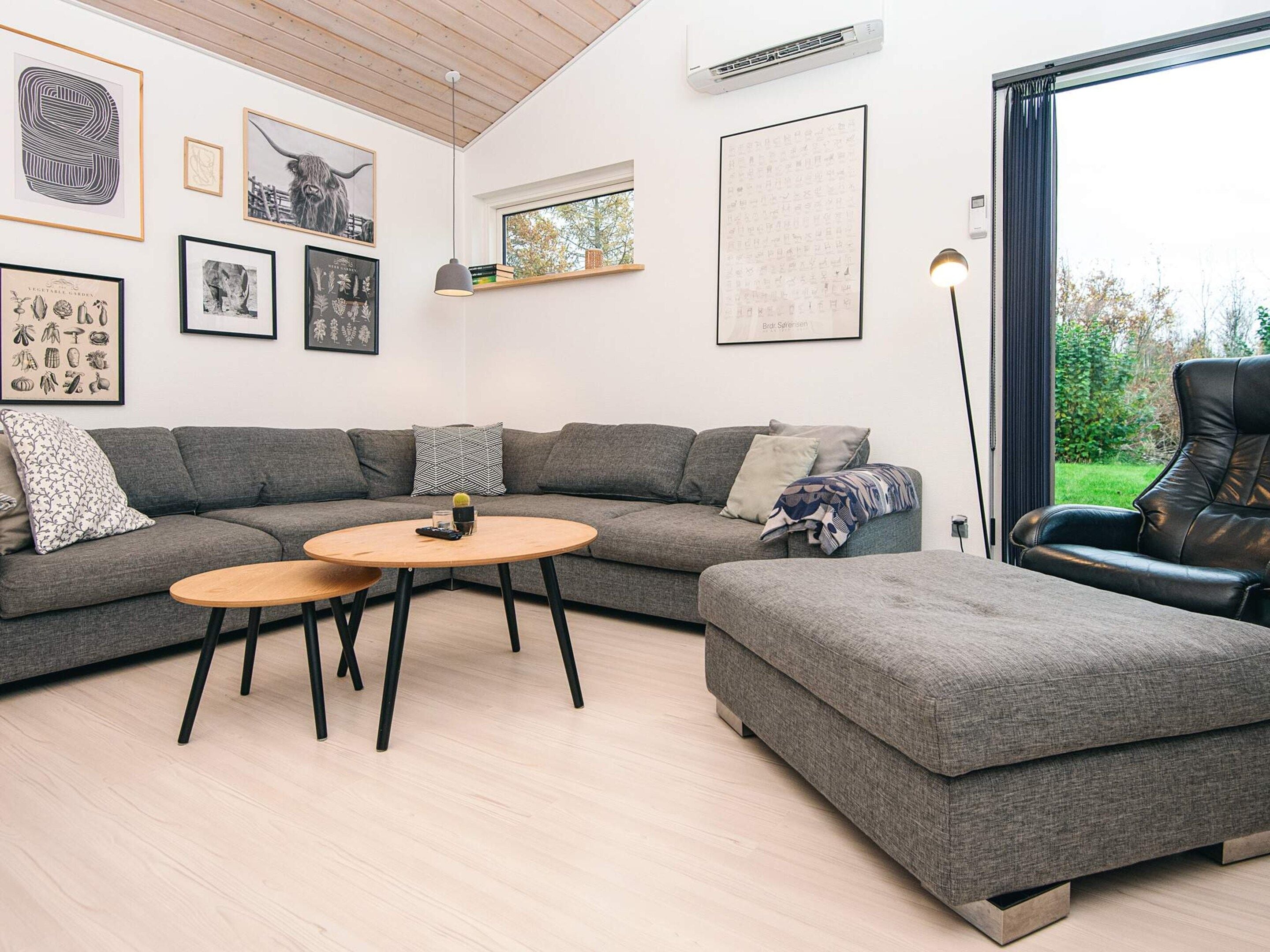 A modern living room with a grey sectional sofa, a wooden coffee table, and a black leather chair.