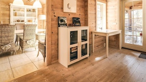 Un intérieur en bois comprenant un coin repas, un meuble blanc aux portes vitrées et une fenêtre offrant une vue agréable.