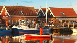 A harbor with boats docked, a red building labeled "GRILL ISMAR", and a clear sky. - Tranquil Retreat With Spa - By Traum Ferienwohnungen (Hemmet)