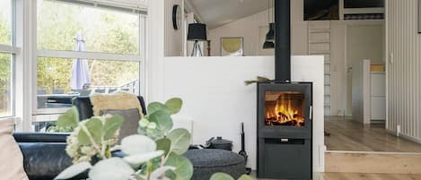 A cozy living room with a black wood-burning stove, a black leather sofa, and a glass coffee table.