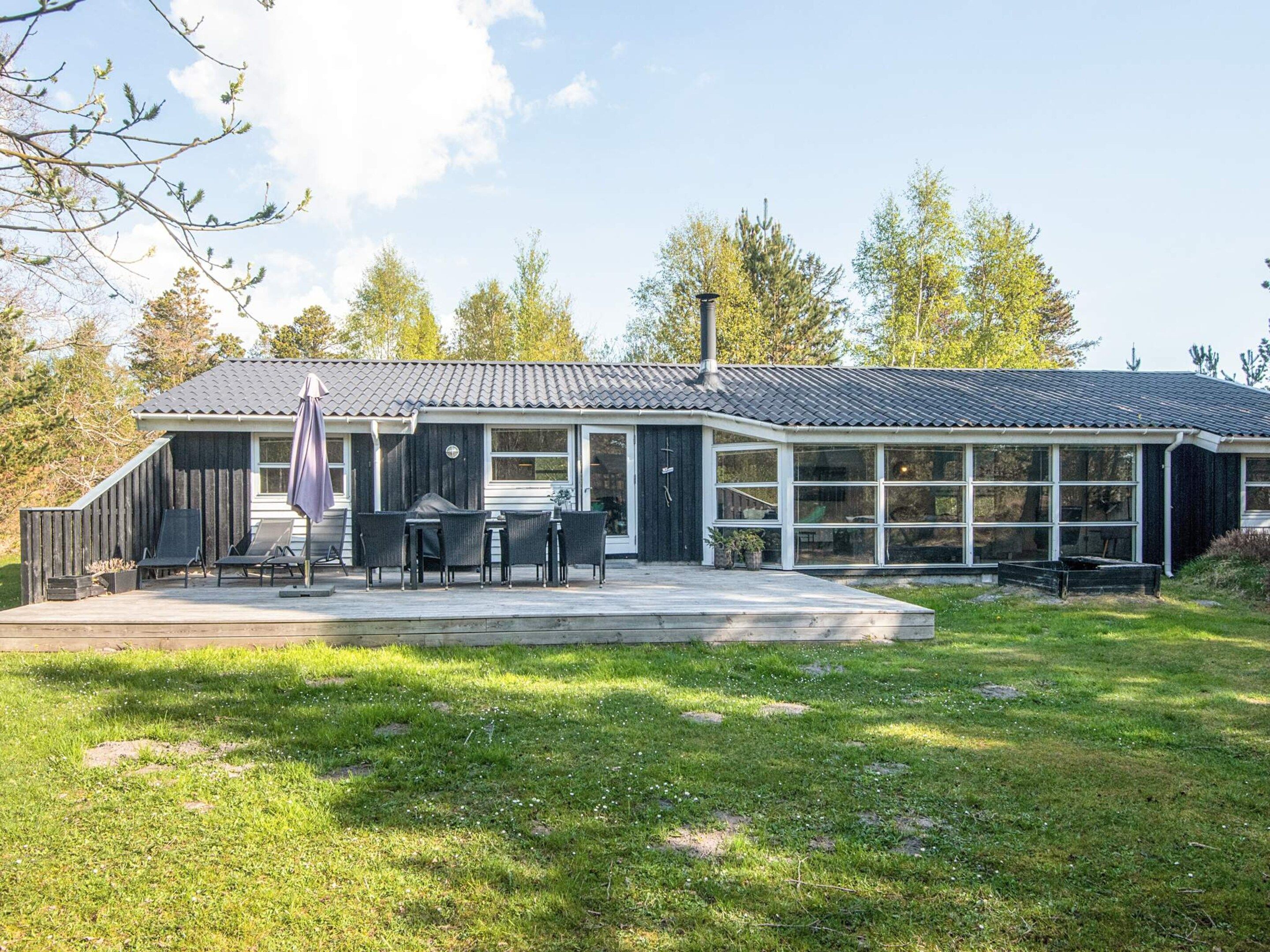 A modern house with a covered patio, outdoor seating, and a large windowed extension.
