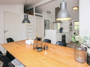 Un comedor con mesa de madera, sillas negras e iluminación colgante.