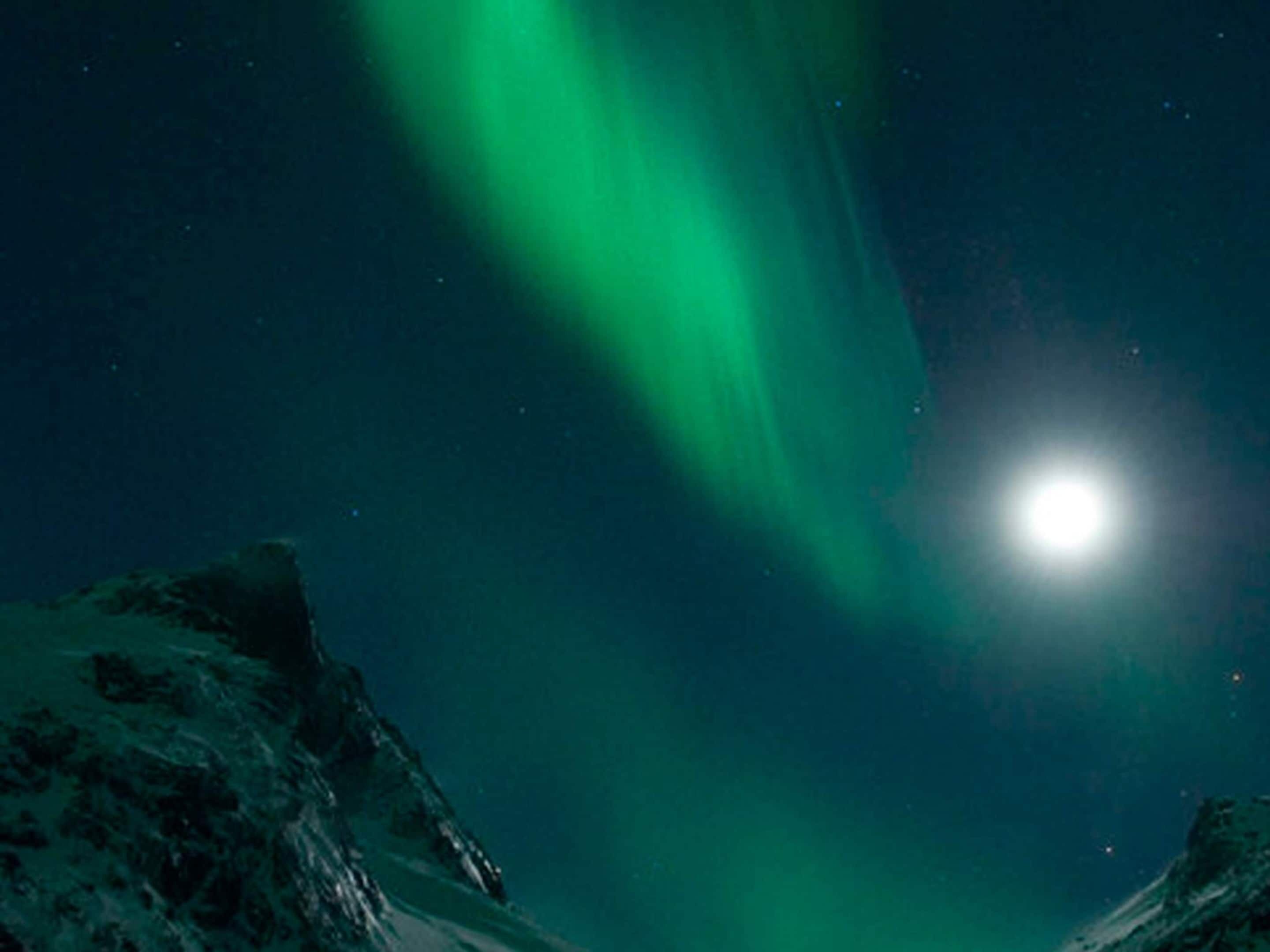 A night sky with the aurora borealis and a bright moon.