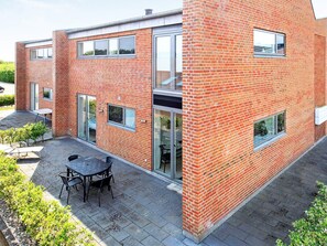 A modern two-story brick building with large windows and a patio area with outdoor seating.