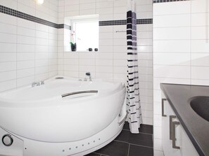 A modern bathroom with a freestanding bathtub, a shower curtain, and a small window above the sink. - 4 Star Holiday Home in Hemmet (Hemmet)
