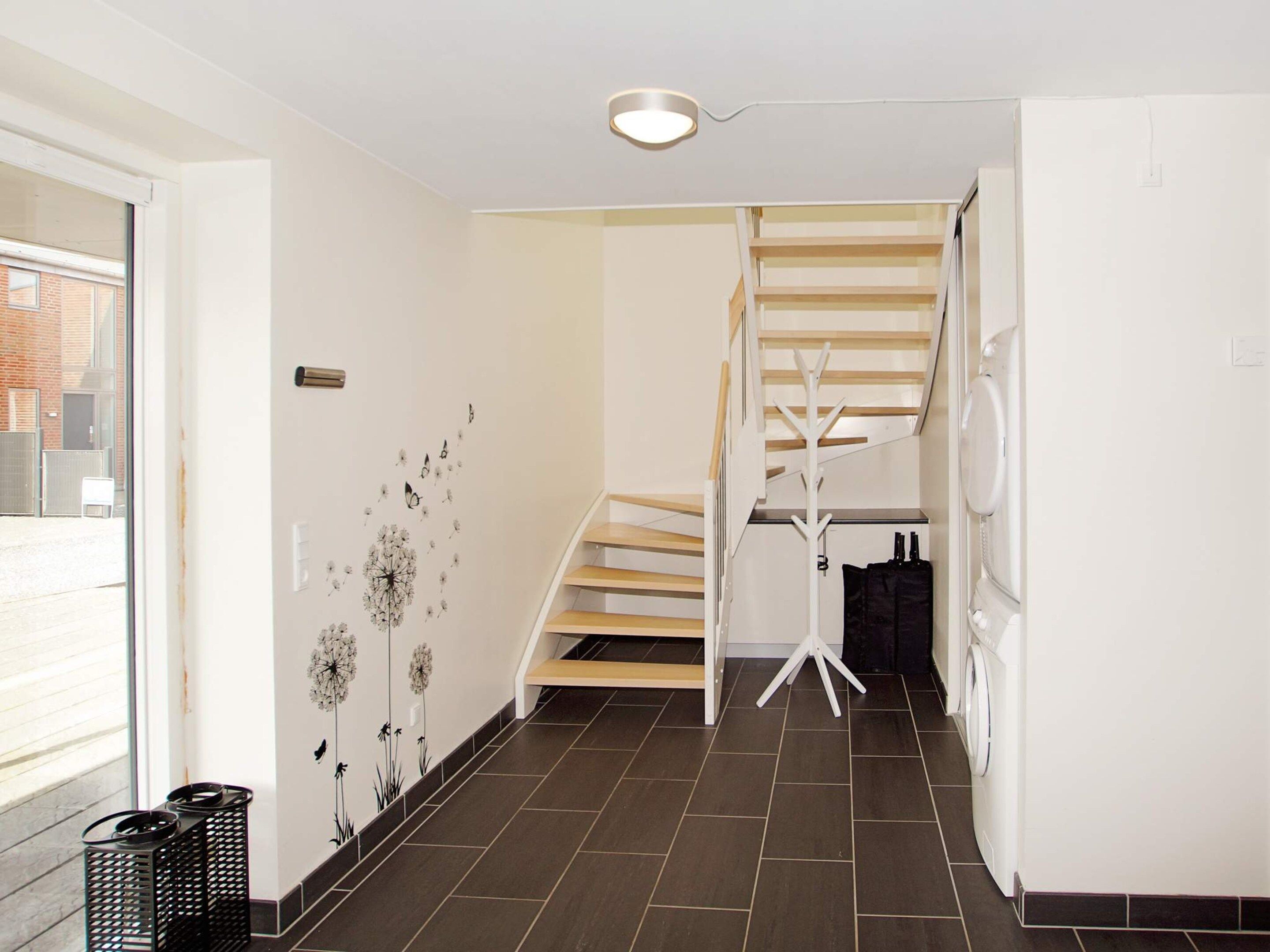 A modern interior with a staircase, a coat rack, and a washing machine.